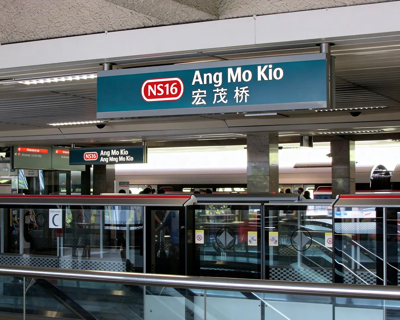Clear and prominent Ang Mo Kio MRT station signage displayed above the platform, guiding passengers with bold lettering and directional information in a well-lit transit environment.
