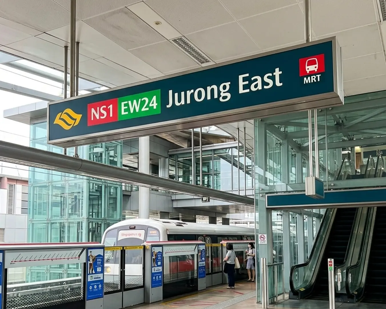 Exterior view of Jurong East MRT train station in Singapore, a busy transport hub with modern architecture and commuters entering and exiting the station.