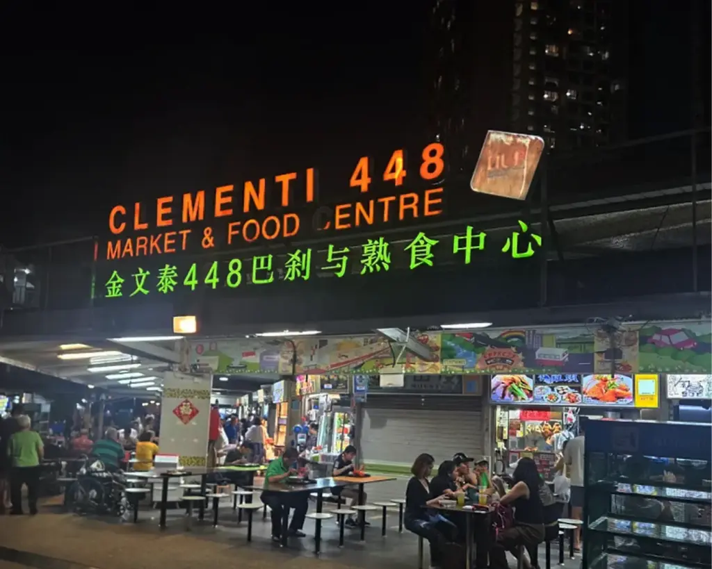 A bustling local hawker centre filled with food stalls and diners, featuring rows of tables, bright signboards, and a lively atmosphere typical of Singapore’s neighbourhood markets.