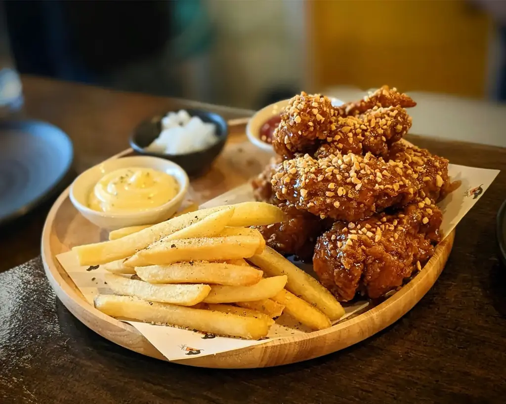 Crispy Korean fried chicken coated in a glossy sauce, served alongside golden fries, creating a satisfying contrast of crunchy texture and rich flavour.