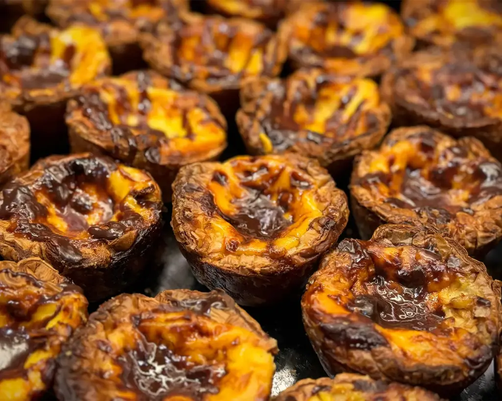 Golden egg tarts with flaky pastry crust and smooth custard filling, a popular Chinese dessert commonly found in bakeries and dim sum restaurants.