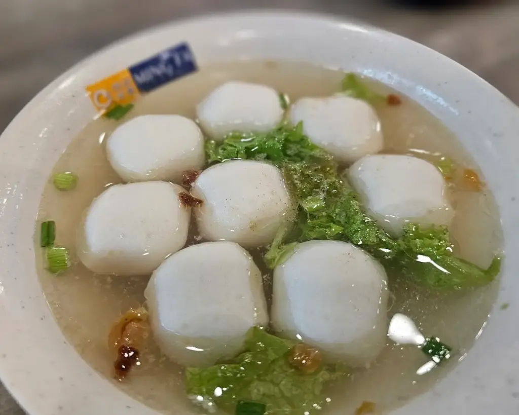 A comforting bowl of springy handmade fishballs served with noodles in a light broth, highlighting freshness and a traditional preparation style.