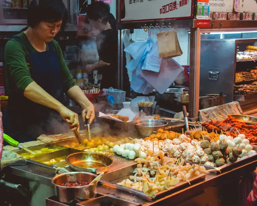 A hawker vendor preparing a dish at a food stall in Singapore, skillfully cooking food for customers in a busy hawker centre environment.