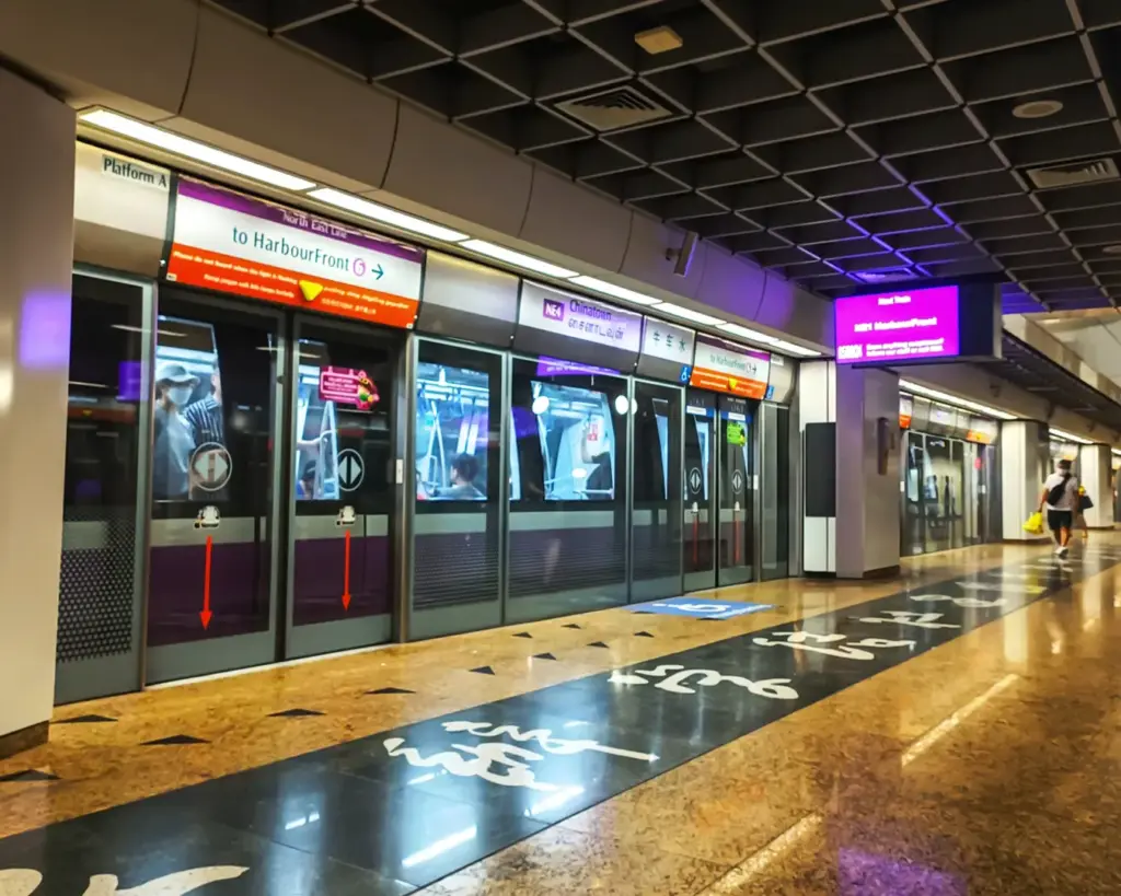 Platform area at Chinatown MRT Station with commuters waiting for the train, featuring clean modern design and clear signage typical of Singapore’s MRT system.
