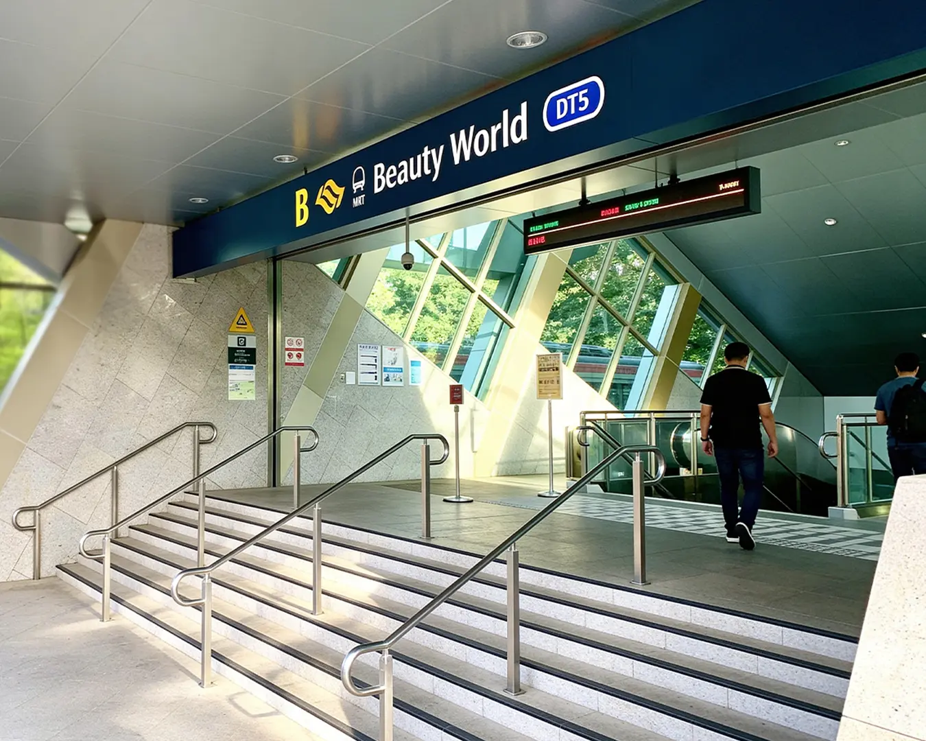 The exterior entrance of Beauty World MRT station with station signage visible, surrounded by nearby buildings and pedestrian walkways.