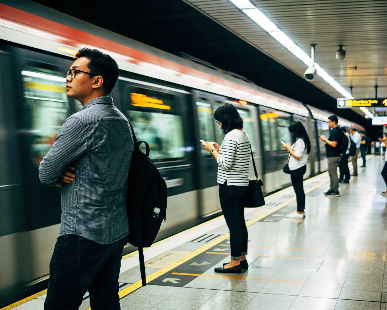 Passengers gathered along a modern train station platform, patiently waiting as they prepared to board the arriving train.