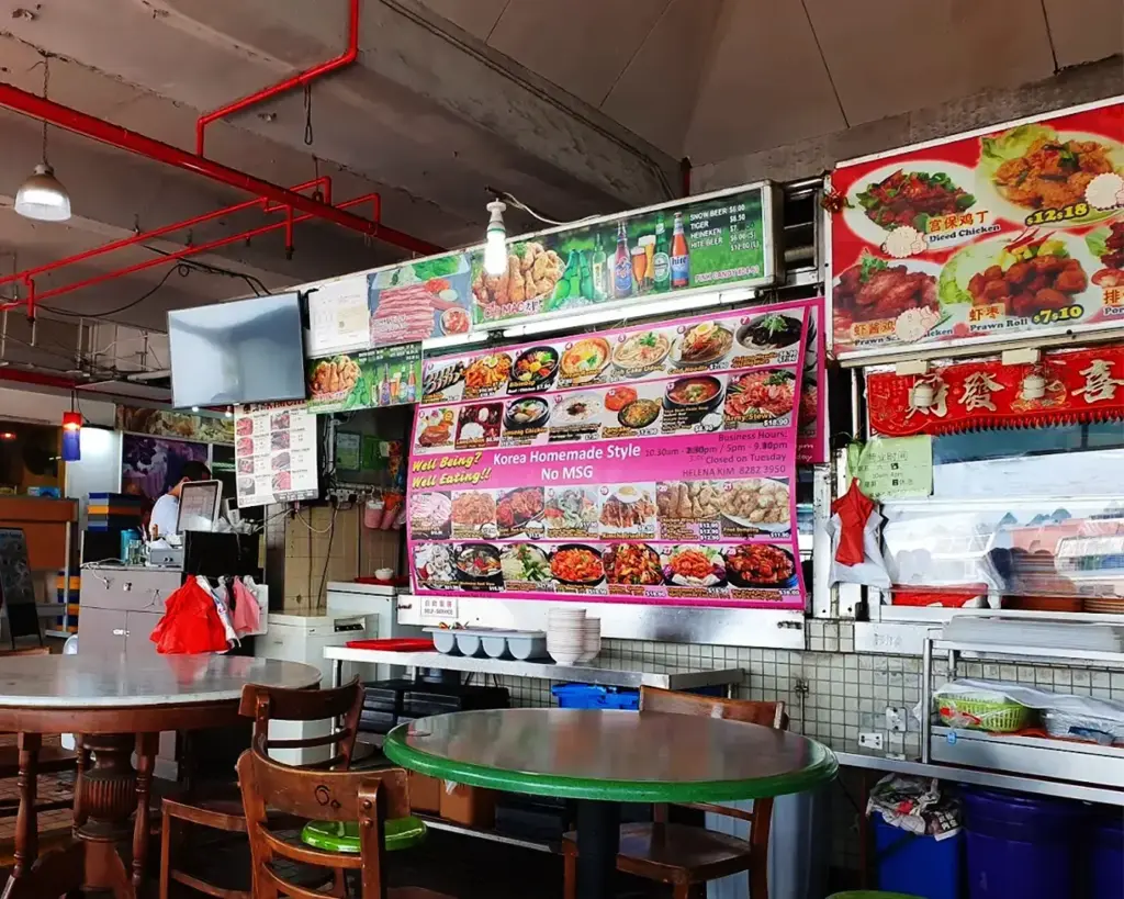Casual eatery interior with colorful menus displaying Korean dishes. Wooden chairs and tables give a cozy atmosphere. Vibrant and inviting.