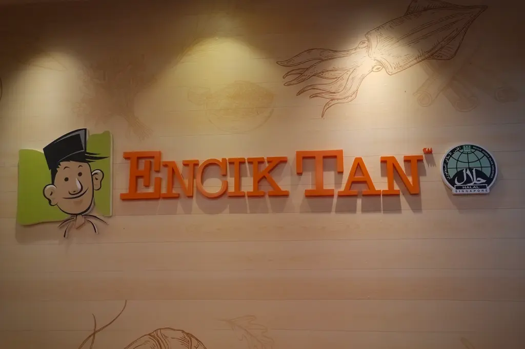 Encik Tan restaurant signage in Singapore featuring halal certification logo and illustrated seafood wall art inside the dining establishment
