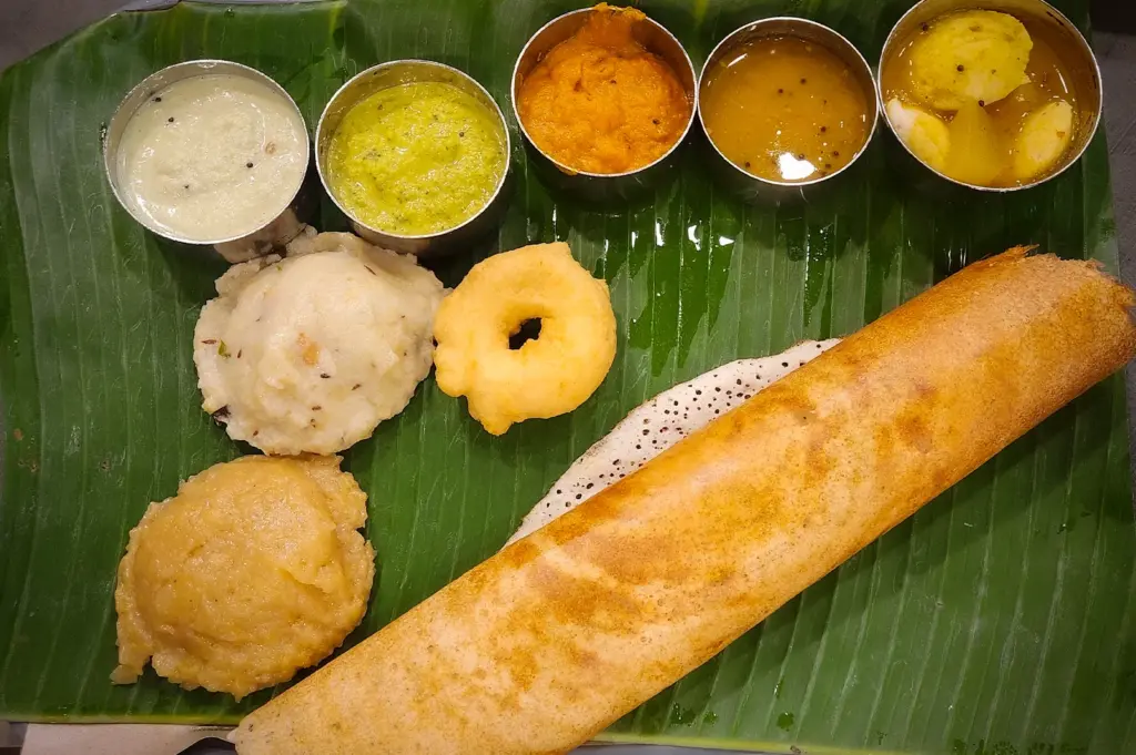 Traditional South Indian meal at Komala Vilas Singapore featuring crispy dosa, idli, vada, chutneys, sambar, and semolina dishes served on a banana leaf platter