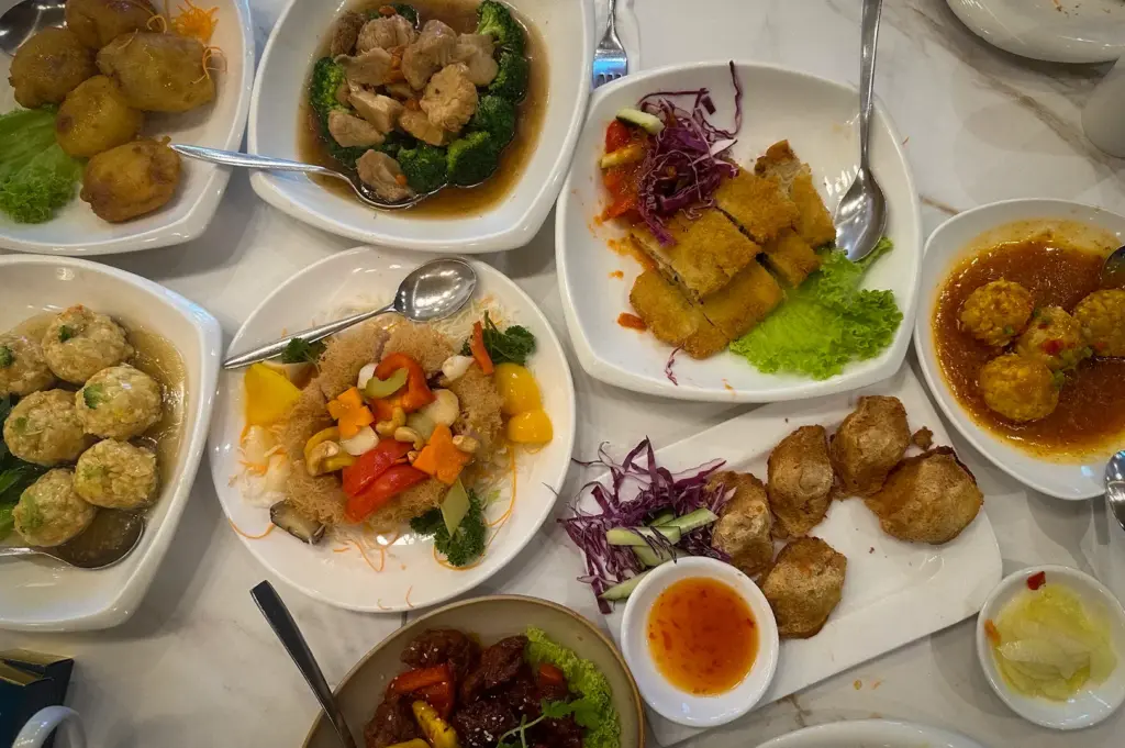 Assorted Chinese vegetarian dishes at Whole Earth Vegetarian Singapore featuring tofu rolls, vegetable stir fry, mock meat dishes, broccoli, yam balls, and fried appetizers served across a restaurant dining table