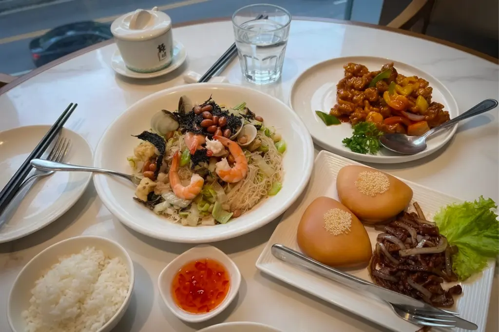 Putien Mitsukoshi BGC meal with fried bee hoon topped with prawns and clams, sweet and sour pork, mantou buns with braised pork, steamed rice, and dipping sauces.