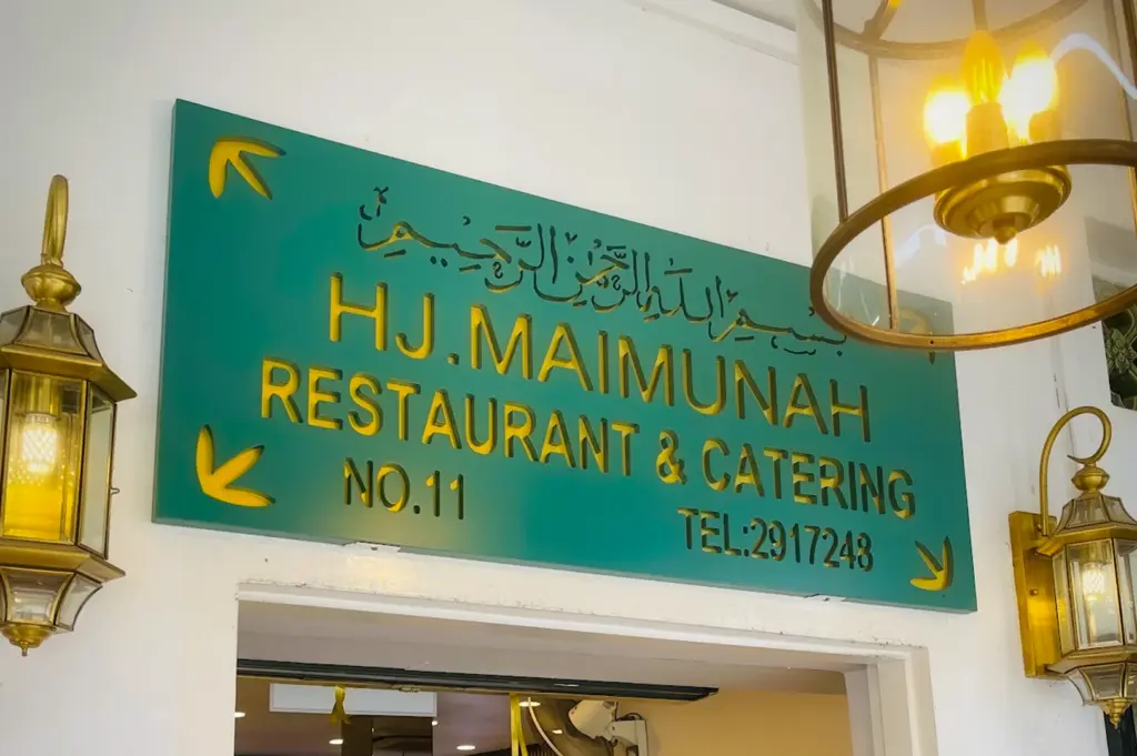 HJ Maimunah Restaurant and Catering signboard in Singapore featuring Arabic calligraphy, gold lettering and decorative lantern lighting above the entrance
