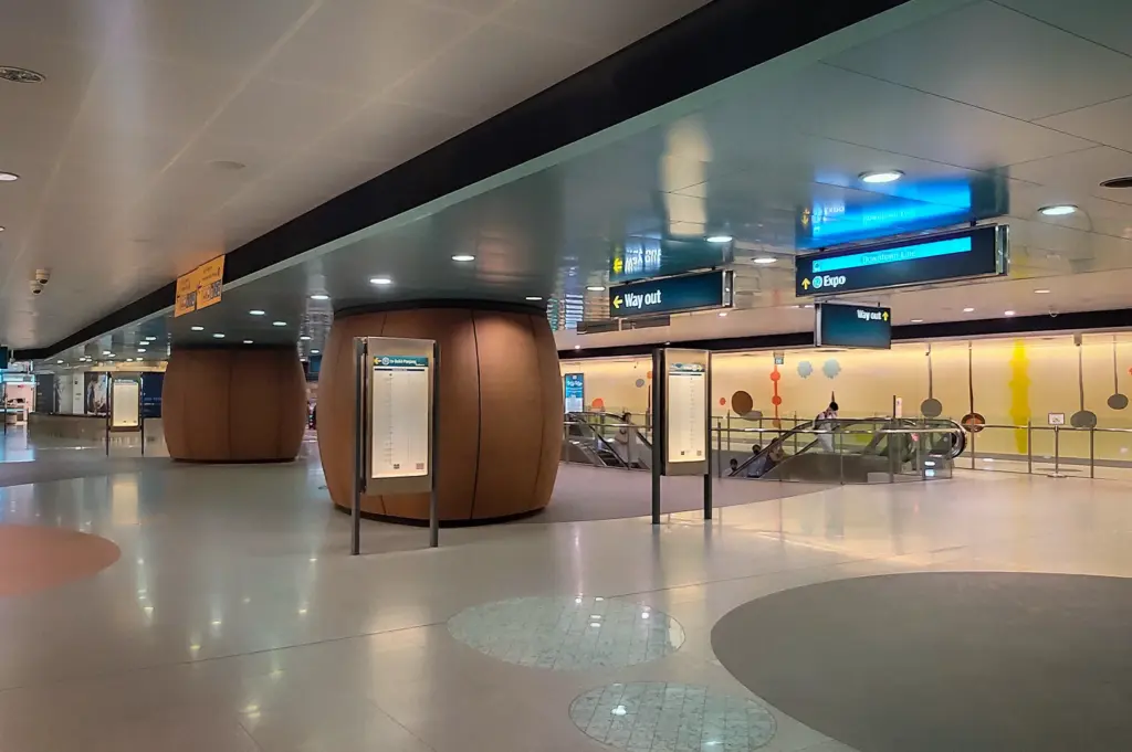 Wide interior view of Telok Ayer MRT station concourse in Singapore with escalators, directional signage, and modern underground transit design