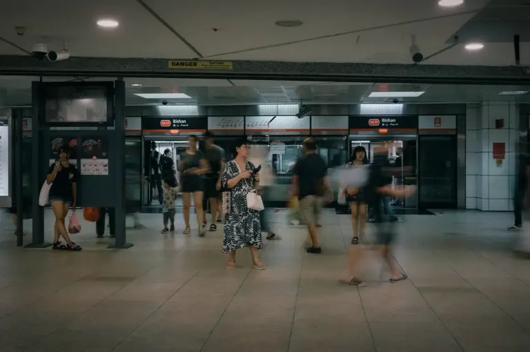 Commuters moving through the concourse of Bishan MRT Station in Singapore, with station signage, platform screen doors, and motion blur capturing the busy pace of daily public transport travel.