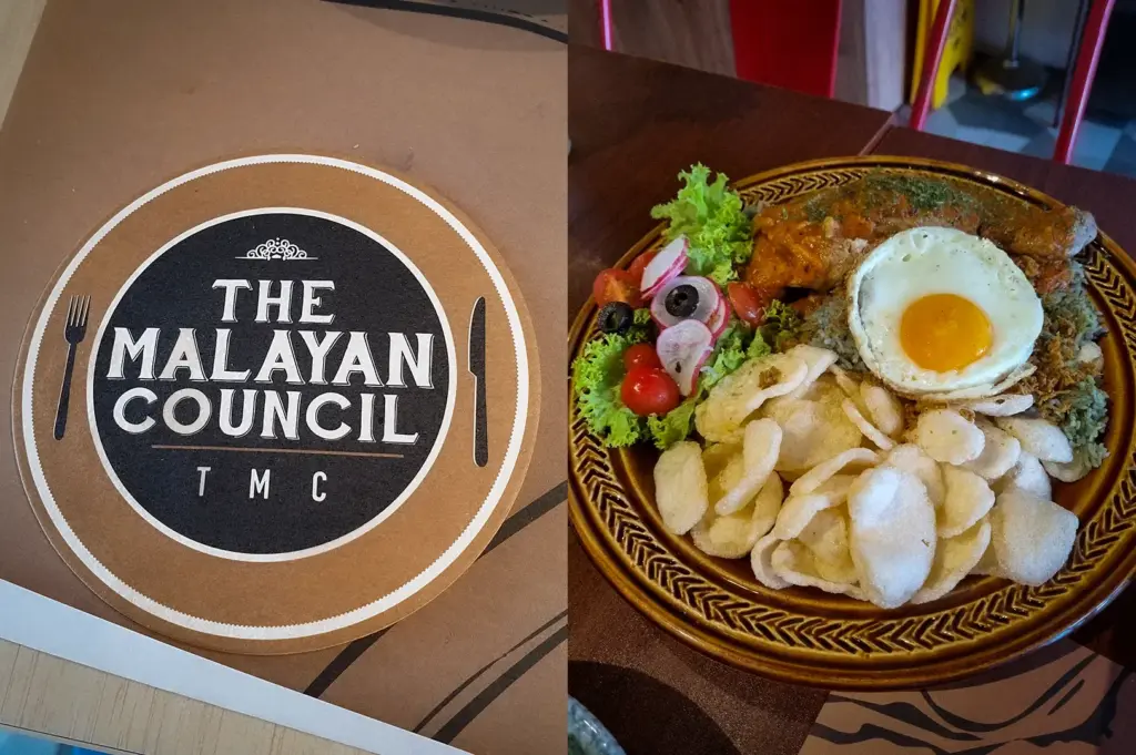 Nasi kerabu with grilled chicken, sunny-side egg, crackers, and fresh salad served at The Malaysian Council Singapore alongside branded restaurant tableware.
