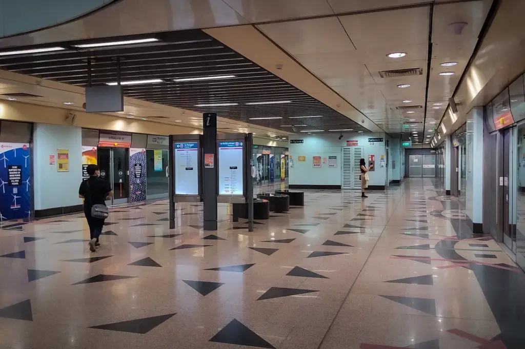 Woodleigh MRT Station platform in Singapore featuring platform screen doors, passenger information displays, and a spacious underground concourse.