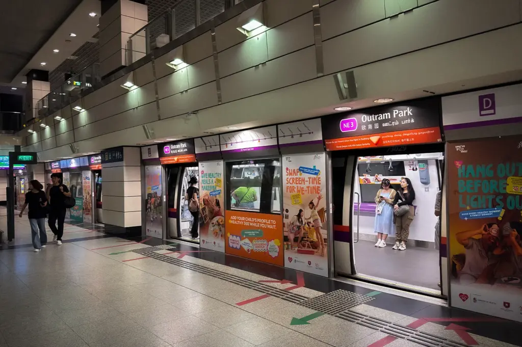 North East Line MRT platform at Outram Park station in Singapore with platform screen doors, train boarding area, and waiting passengers.