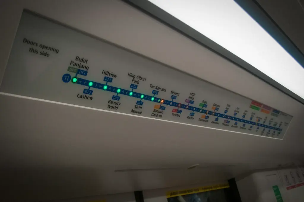 Singapore Downtown Line MRT route map displayed inside a train carriage, showing station connections, interchange stations, and real-time route information for commuters.
