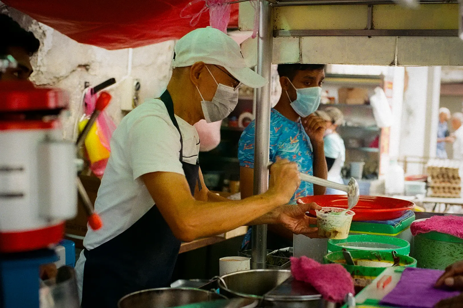 Hawker preparing a freshly served local dish at a busy Singapore hawker food stall, showcasing authentic street food culture and traditional food preparation.