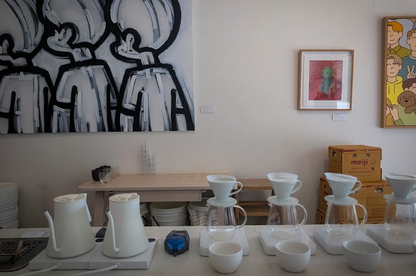 Minimalist interior of Apartment Coffee in Singapore featuring pour-over coffee brewers, modern counter setup, and contemporary artwork on the café walls.
