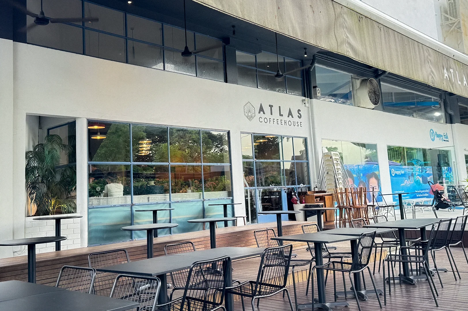 Exterior of Atlas Coffeehouse in Bukit Timah, Singapore, featuring outdoor seating, modern café frontage, and a spacious wooden deck.