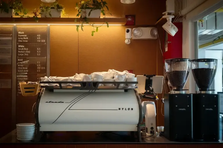 Interior of Nylon Coffee Roasters Singapore featuring a professional espresso bar, coffee grinders, menu board, and modern specialty coffee brewing station.