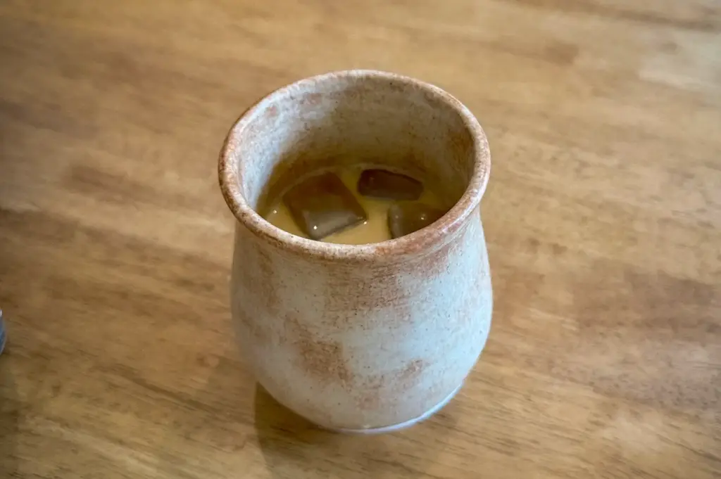 Iced coffee served in a handcrafted ceramic cup at Apartment Coffee in Singapore, presented on a minimalist wooden café table.