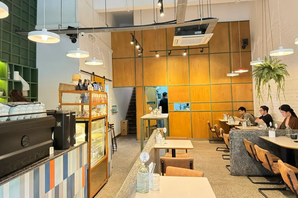 Modern interior of Atlas Coffeehouse in Bukit Timah, Singapore, featuring high ceilings, minimalist décor, coffee bar, and comfortable dining seating.