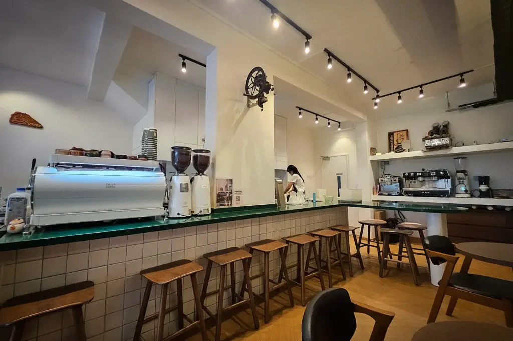 Interior of Tiong Hoe Specialty Coffee in Singapore featuring an espresso bar, coffee grinders, bar seating, brewing equipment, and a bright minimalist café atmosphere.