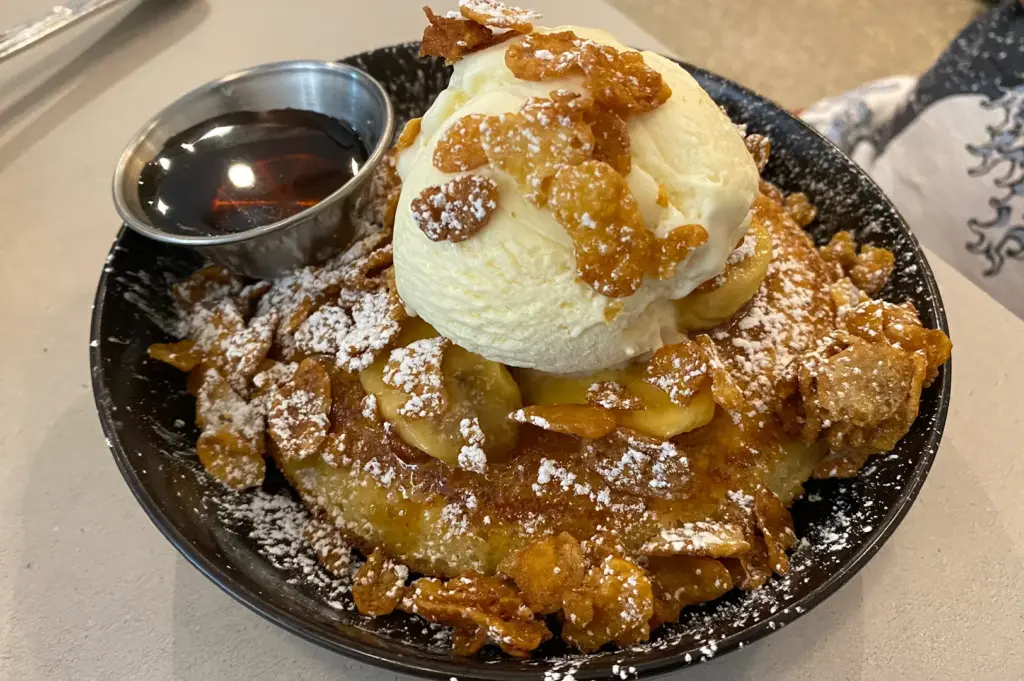 Butterscotch banana pancakes topped with vanilla ice cream, caramelized cornflakes, powdered sugar, and maple syrup served at Atlas Coffeehouse in Bukit Timah, Singapore.