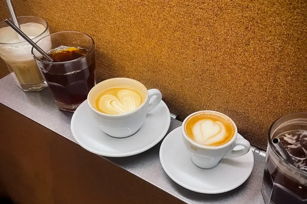 Coffee selection at Nylon Coffee Roasters Singapore featuring espresso, latte, iced coffee, and milk-based specialty drinks with latte art on a minimalist counter.
