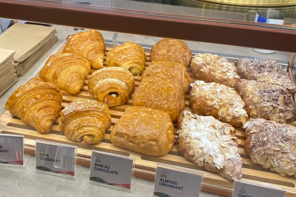 Fresh croissants, pain au chocolat, kaya croissants, and almond pastries displayed at the Prairie by Craftsmen bakery counter in Singapore.