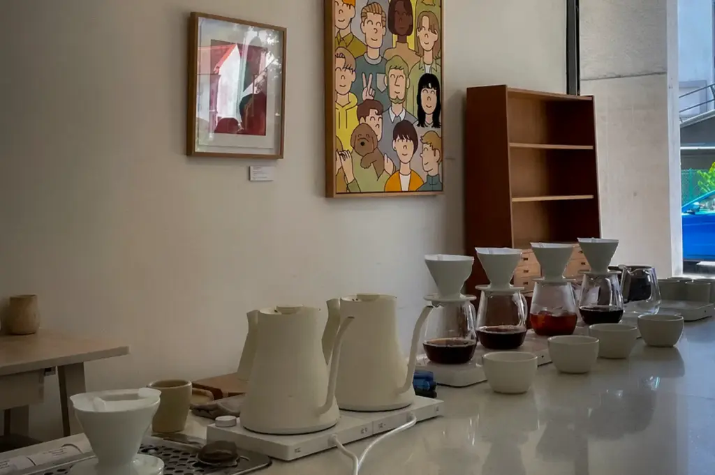 Pour-over coffee counter at Apartment Coffee Singapore featuring ceramic drippers, coffee servers, minimalist interior, and contemporary artwork in a bright café space.