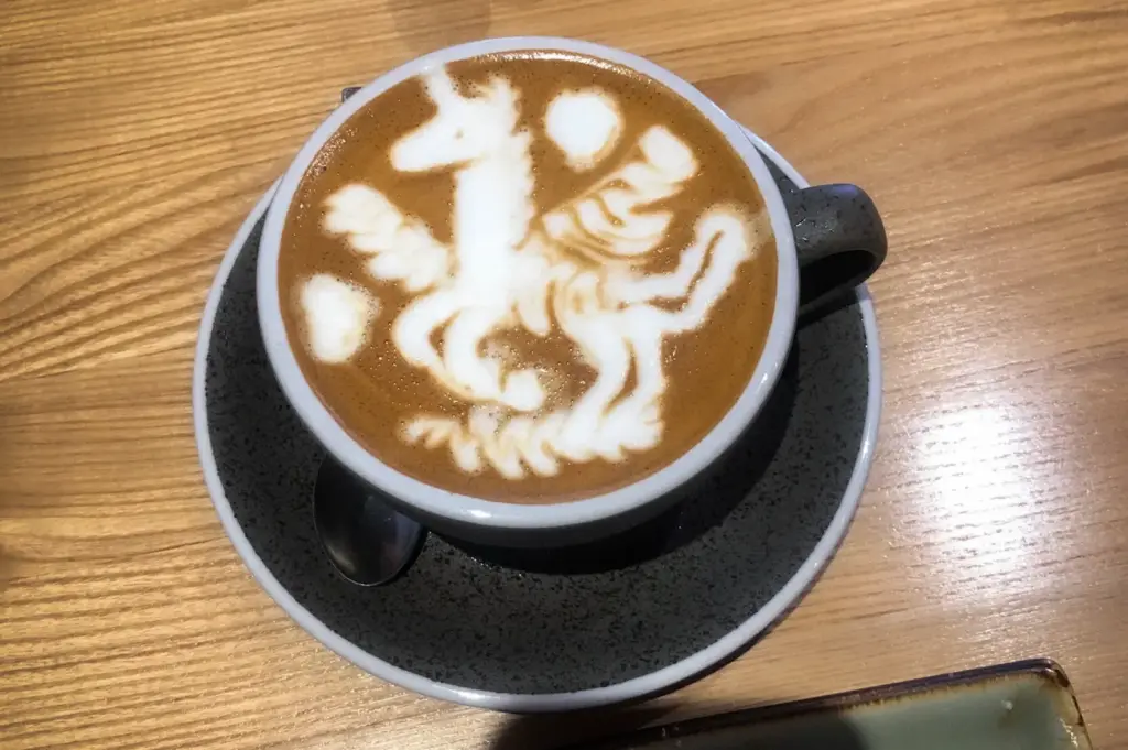 Latte with intricate latte art served at Prairie by Craftsmen in Singapore, presented on a wooden table in a modern café setting.