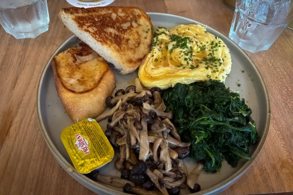 Creamy scrambled eggs with toasted sourdough, sautéed mushrooms, spinach, and hash browns served at The Brewing Ground Singapore.