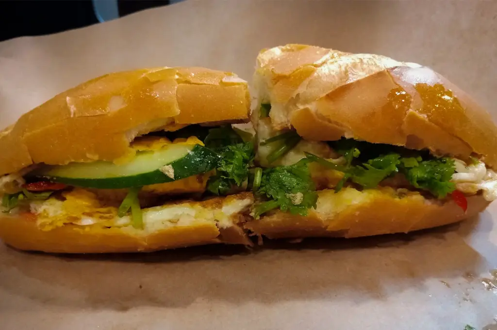 Vietnamese banh mi sandwich from TON Coffee Singapore, filled with grilled meat, fried egg, fresh cucumber, cilantro, and vegetables in a crispy baguette.