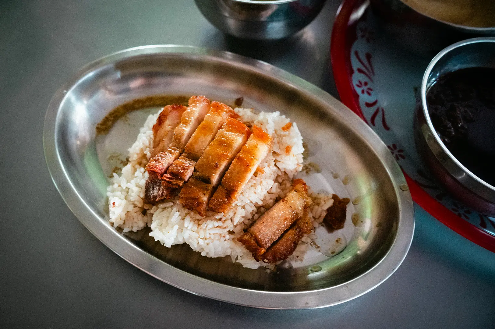Singaporean roast chicken rice served with fragrant white rice on a metal plate
