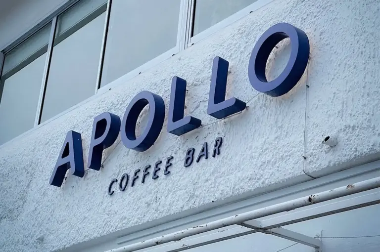 Exterior signage of Apollo Coffee Bar in Serangoon Gardens, Singapore, featuring the café's minimalist white facade and bold blue lettering above the entrance.