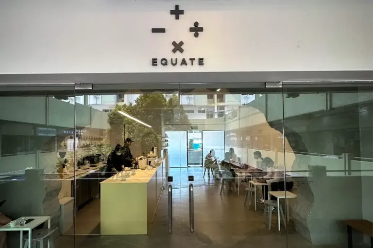 Equate Coffee cafe in Singapore with a minimalist interior, glass entrance, coffee counter, seating area, and distinctive mathematical symbol logo.