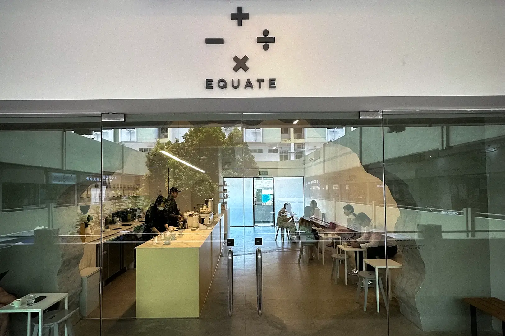 Equate Coffee cafe in Singapore with a minimalist interior, glass entrance, coffee counter, seating area, and distinctive mathematical symbol logo.
