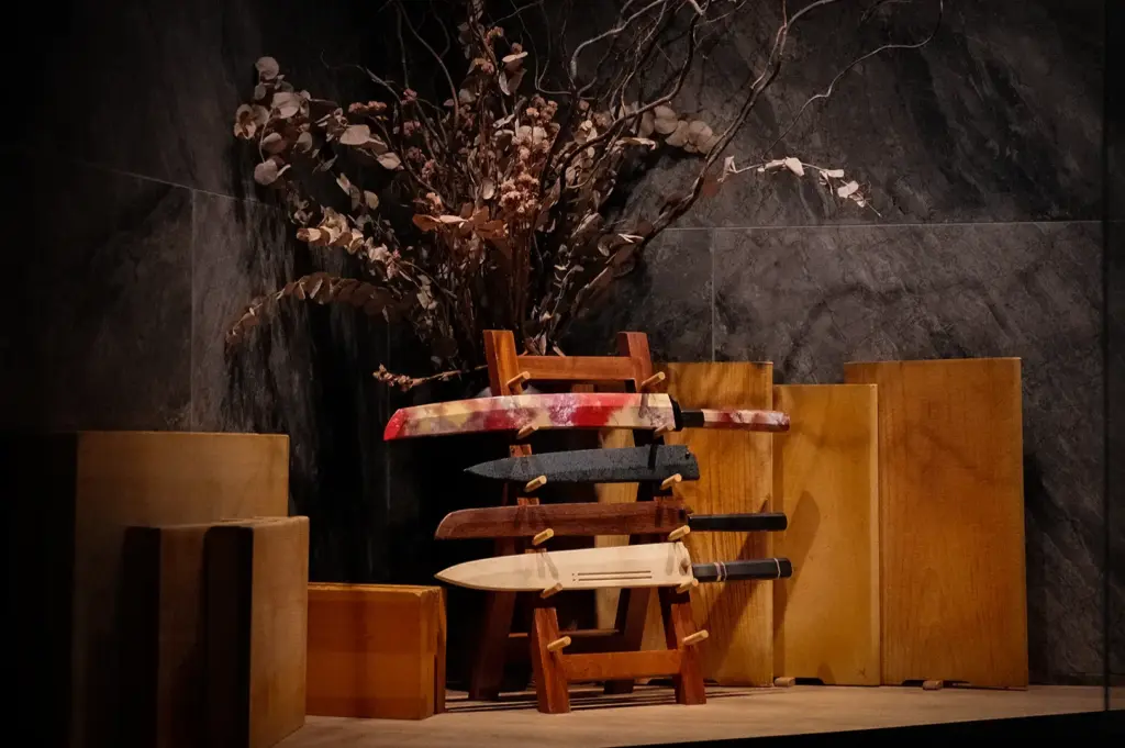 Sushi to Sumi Singapore interior with Japanese knives displayed on a wooden stand, natural wood decor, and dark stone walls