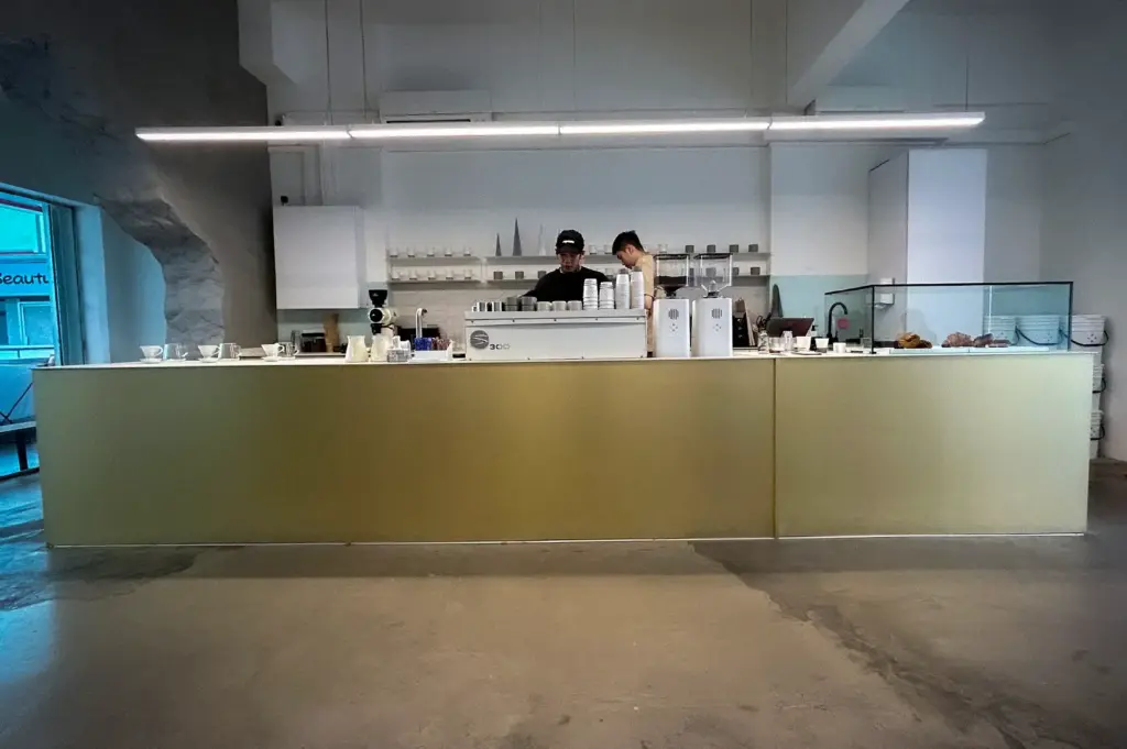 Equate Coffee Singapore interior with a minimalist white coffee counter, espresso machine, pastry display, and baristas preparing drinks.