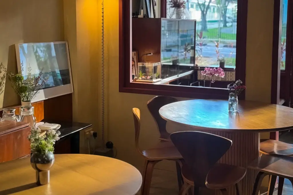 Shu Bakery Space@Kovan Singapore interior with wooden tables, chairs, floral arrangements, and warm natural light.