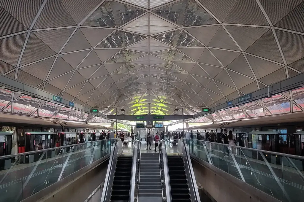 Singapore MRT station platform with trains, escalators, and geometric vaulted roof structure