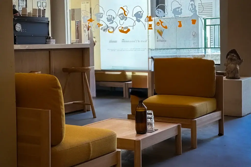 Kurasu Singapore interior with minimalist Japanese design, warm wooden furniture, and mustard yellow lounge chairs