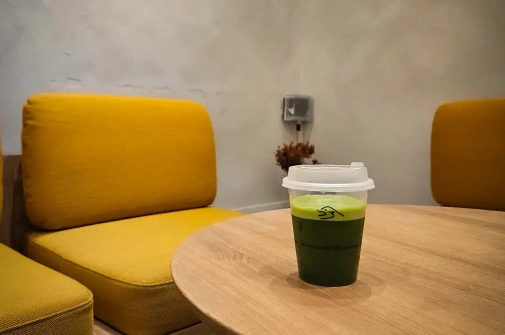 Kurasu Singapore cafe interior with mustard yellow chairs, wooden table, and matcha drink