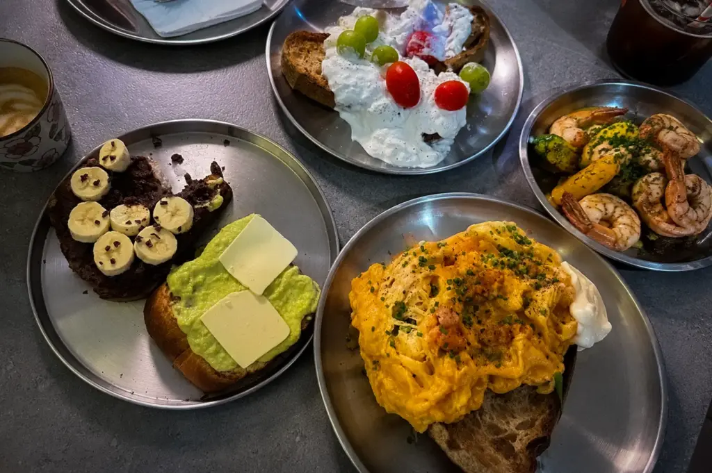 Shu Bakery Space@Kovan Singapore breakfast spread with scrambled eggs on toast, avocado toast, banana chocolate toast, creamy fruit toast, and prawns.