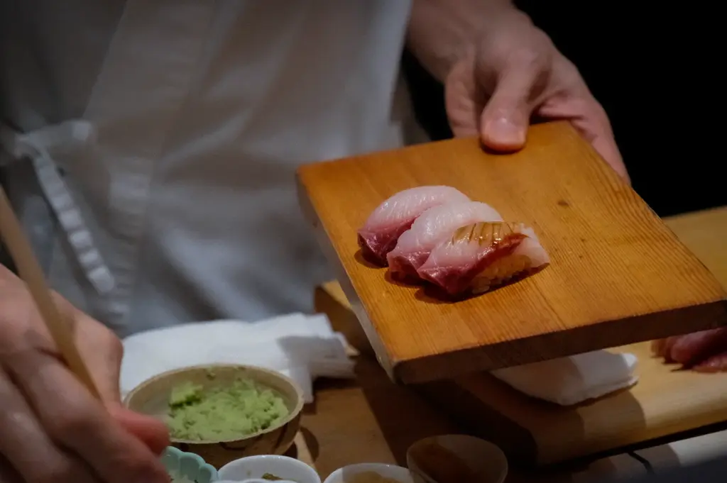 Sushi to Sumi Singapore chef serving fresh nigiri sushi on a wooden plate with wasabi and Japanese condiments