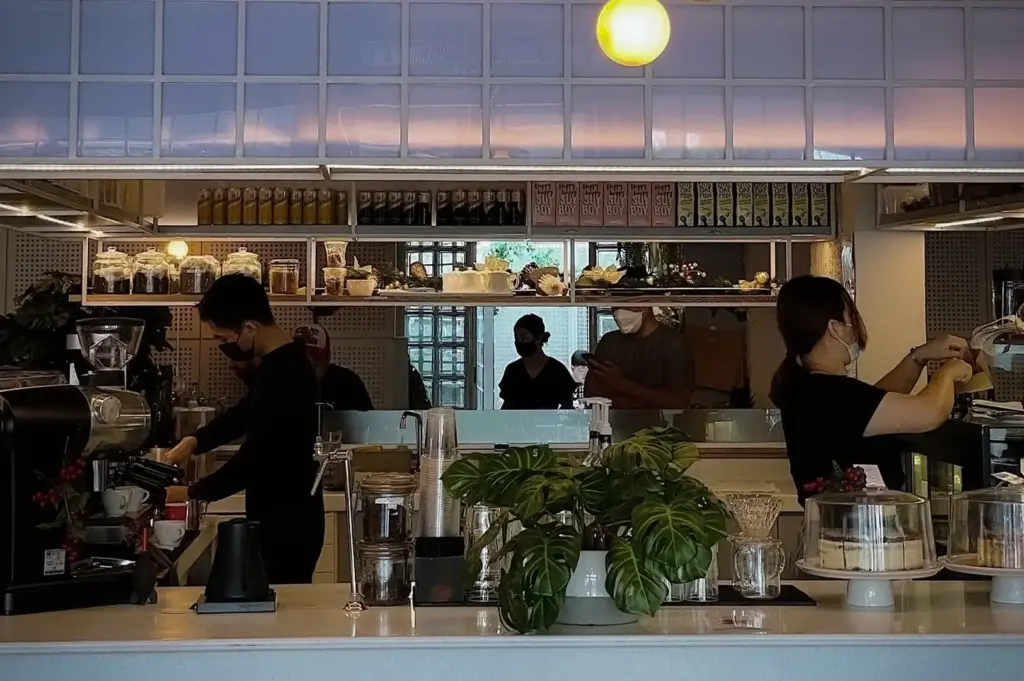 Baristas preparing specialty coffee behind the bright minimalist counter at Apollo Coffee Bar in Serangoon Gardens, Singapore, with espresso machines, pastries, and modern café décor.