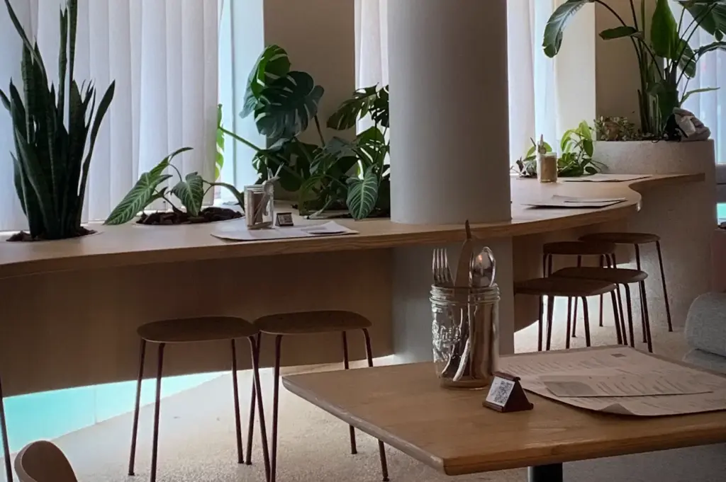 Lola’s Cafe Holland Village interior with wooden tables, stools, lush plants, and bright natural light in Singapore